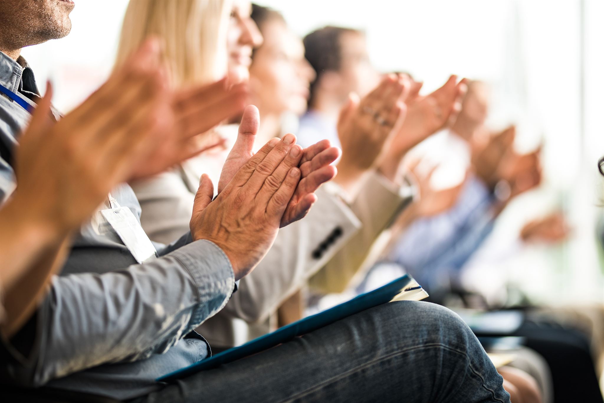 Row-of-seated-people-clapping-hands-at-work-event